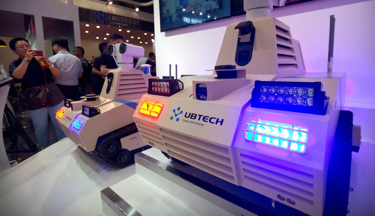 Seorang pengunjung mengambil gambar robot keamanan buatan UBTECH di Konferensi Robot Dunia 2018 di Beijing, China, Rabu (15/8). (AP Photo/Mark Schiefelbein)