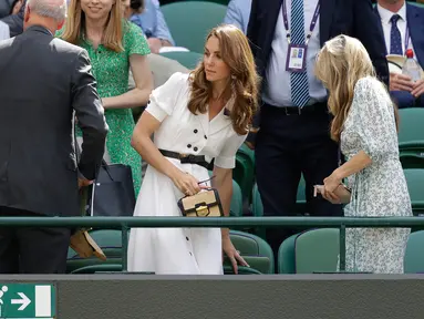 Duchess of Cambridge, Kate Middleton berdiri usai menyaksikan pertandingan babak pertama turnamen Wimbledon 2019 antara petenis Inggris, Johanna Konta melawan petenis Romania, Ana Bogdan di London (2/7/2019). Kate Middleton tampil cantik dalam balutan gaun putih. (AP Photo/Kirsty Wigglesworth)