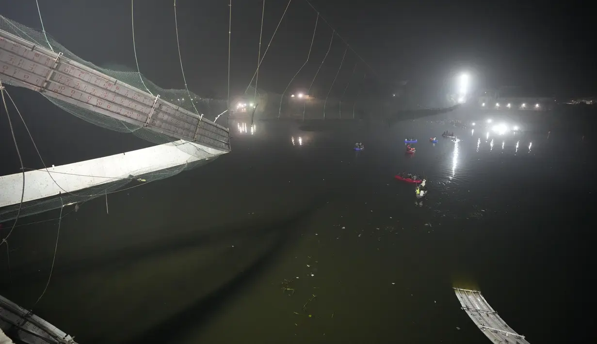 Tim penyelamat di kapal mencari di sungai Machchu di sebelah jembatan kabel yang runtuh di kota Morbi di negara bagian barat Gujarat, India, Senin, 31 Oktober 2022. Sedikitnya 81 orang tewas akibat kejadian tersebut. (AP/Ajit Solanki)