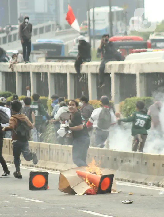 Massa aksi demo mahasiswa berlari menghindari tembakan gas air mata oleh aparat keamanan di depan Gedung DPR, Jakarta, Senin (11/4/2022). Mahasiswa yang tergabung dalam aliansi BEM SI menggelar unjuk rasa besar-besaran di depan Gedung DPR/MPR RI, Senin ini. (Liputan6.com/Angga Yuniar)