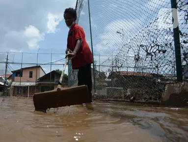 Warga membersihkan lumpur sisa banjir di Kelurahan Rawa Jati, Jakarta, Selasa (9/2/2021). Endapan lumpur yang mengendap akibat luapan Kali Ciliwung. (merdeka.com/Imam Buhori)