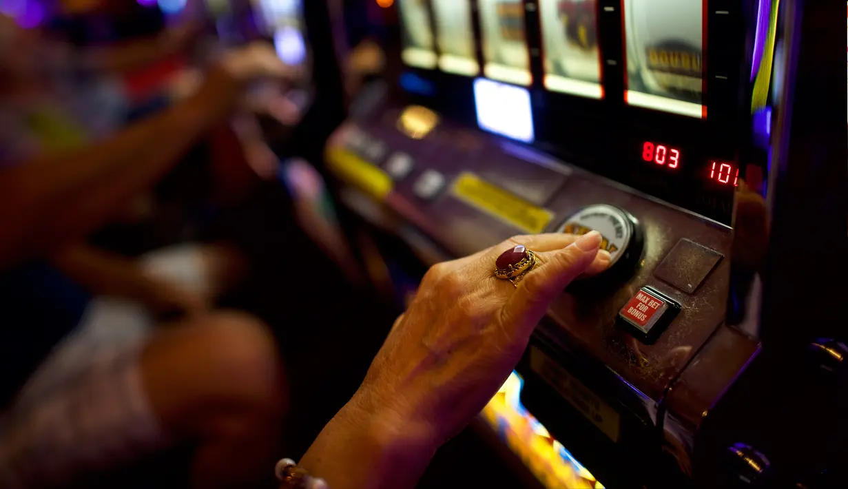 Seorang wanita lansia menekan tombol saat bermain mesin slot di Dover Downs Casino, Delaware (5/6). Legalisasi ini dilakukan sejak keputusan Mahkamah Agung yang mencabut larangan federal setelah 25 tahun lalu. (Mark Makela/Getty Images North America/AFP)