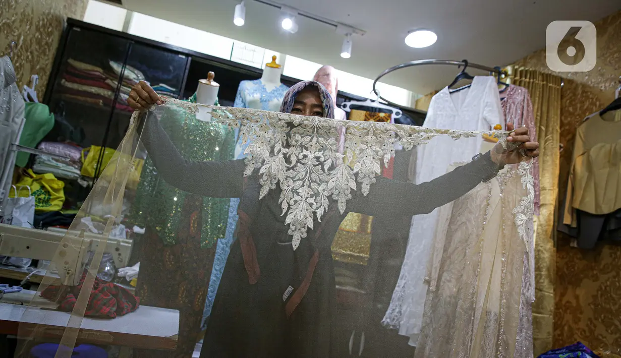 Penjahit menunjukkan pakaian di Pasar Mayestik, Jakarta, Selasa (11/5/2021). Menjelang Lebaran, pesanan jahitan turun sebesar 50 persen akibat pandemi COVID-19 serta larangan pemerintah terkait mudik luar kota dan mudik lokal. (Liputan6.com/Faizal Fanani)