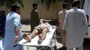 Seorang pria Afghanistan yang terluka dibawa dengan tandu oleh para sukarelawan di dekat lokasi ledakan bom bunuh diri dan serangan bersenjata di Jalalabad, Selasa (31/7). Sebanyak 15 orang tewas akibat insiden tersebut. (AFP/NOORULLAH SHIRZADA)