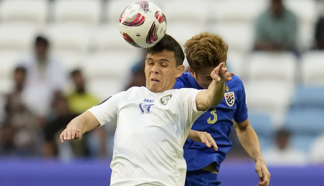 Gelandang Timnas Uzbekistan, Azizbek Turgunboev (depan) memenangi duel udara dengan bek Thailand, Theerathon Bunmathan pada laga babak 16 besar Piala Asia 2023 di Al Janoub Stadium, Al Wakrah, Qatar, Selasa (30/1/2024). (AP Photo/Aijaz Rahi)