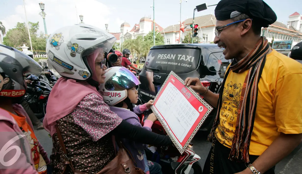 Komunitas Gerakan Literasi Aksara Jawa membagikan kalender berhuruf Jawa kepada  pengunjung  pada peringatan Hari Aksara Internasional ke-50 di Titik Nol km, Yogyakarta, Kamis (8/9). (Liputan6.com/ Boy Harjanto)