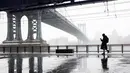 Seorang pejalan kaki melintas di dekat jembatan Manhattan saat badai salju di bawah drive Franklin Delano Roosevelt di New York (21/3). Badai salju yang melanda sebagian Amerika Serikat telah membawa salju dan angin kencang. (AP Photo / Mary Altaffer)