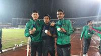 Kiper Timnas Indonesia U-19, Muhammad Riyandi, foto dengan medali perunggu di tengah guyuran hujan di Stadion Thuwunna, Yangon, Minggu (17/9/2017). (Bola.com/Aning Jati)
