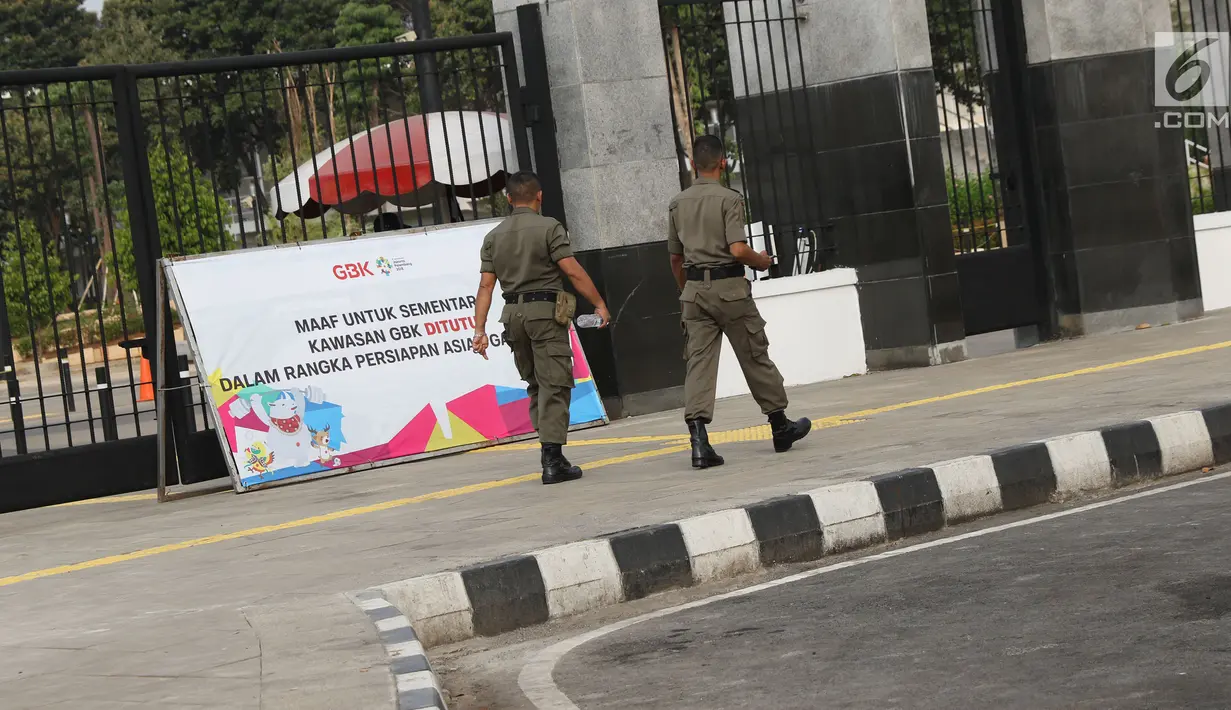 Petugas Satpol PP melintas di salah satu pintu masuk kawasan Gelora Bung Karno, Jakarta, Jumat (20/7). Untuk memperlancar proses persiapan Asian Games 2018, kawasan GBK kembali ditutup untuk umum. (Liputan6.com/Helmi Fithriansyah)