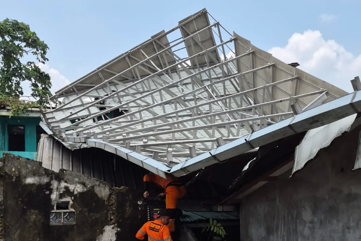 Atap bangunan sekolah yang tak digunakan terhempas angin kencang dan menimpa rumah warga di Kota Bogor. (Liputan6.com/Achmad Sudarno)