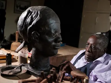 Edward Njenga bekerja memperbaiki patung karyanya yang berjuluk 'Women's Guild Member (2008)' di bengkelnya, Nairobi, Kenya, Senin (12/3). Njenga adalah salah satu pematung terkemuka asal Afrika Timur.  (AFP PHOTO/Yasuyoshi CHIBA)