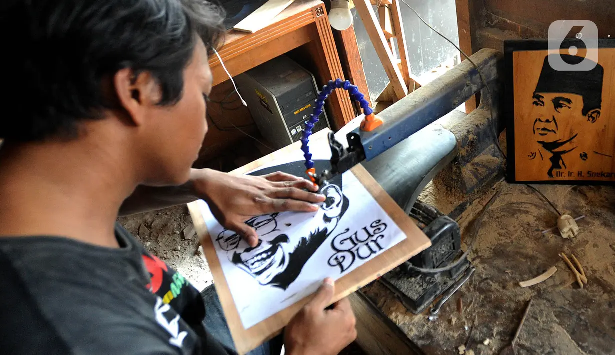 Perajin membuat kerajinan siluet kayu dari wajah tokoh nasional di kawasan Jalan Limo Raya, Depok, Jawa Barat, Rabu (20/11/2019). Siluet yang terbuat dari kayu limbah industri ini dijual dengan harga Rp 200 ribu hingga Rp 500 ribu dan dikerjakan sesuai foto dari pemesan. (merdeka.com/Arie Basuki)