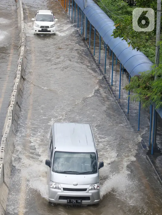 Sejumlah kendaraan melintasi Gerbang Tol Karang Tengah Barat 2 yang masih terendam banjir, Tangerang, Banten, Kamis (2/1/2020). Banjir setinggi betis orang dewasa masih menggenangi Gerbang Tol Karang Tengah Barat 2. (Liputan6.com/Angga Yuniar)