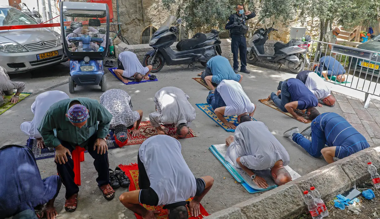 Anggota pasukan keamanan Israel berjaga saat seorang jemaah Palestina melaksanakan salat Jumat selama bulan suci Ramadan di tengah krisis pandemi coronavirus di luar kompleks masjid al-Aqsa di Kota Tua Yerusalem (15/5/2020). (AFP/Ahmad Gharabli)
