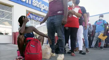 Migran, sebagian besar dari Haiti, menunggu bus setelah mereka diproses dan dibebaskan setelah menghabiskan waktu di kamp darurat dekat Jembatan Internasional di Del Rio, Texas, Minggu (19/9/2021). (AP Photo/Eric Gay)