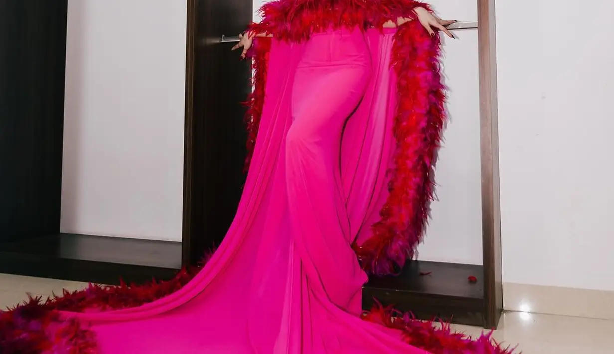 Pesona unik Mahalini Raharja pakai sebuah dress panjang berwarna pink. Dress ini memiliki detail seperti cape yang menjuntai panjang hingga ke lantai dengan ujung bulu-bulu berwarna merah. [Foto: Instagram/mahaliniraharja]