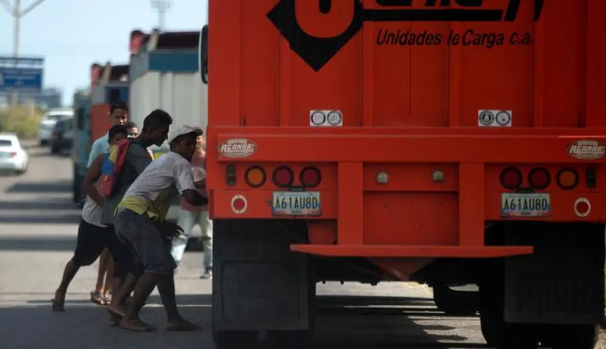 Sejumlah warga mencoba mencuri beras dari truk kargo yang tiba di pelabuhan di Puerto Cabello, Venezuela, Selasa (23/1). Penjarahan sporadis, kerusuhan pangan dan protes yang didorong oleh kelaparan telah melonjak di Venezuela. (AP Photo/Fernando Llano)