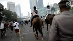 Pengunjung menunggang kuda milik satuan polisi berkuda Polda Metro Jaya di Bundaran HI, Jakarta, Minggu (18/3). Kuda-kuda itu diterjunkan untuk memberi pengenalan terhadap satuan polisi berkuda yang dimiliki Polda Metro Jaya. (Liputan6.com/Faizal Fanani)