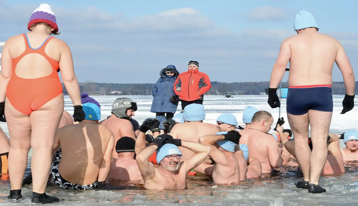 Orang-orang menyaksikan penggemar renang es di Danau Zalew Zegrzynski di Nieporet, Polandia, Minggu (25/2). Kini, Polandia bersuhu -8 derajat Celsius pada siang dan turun ke -16 derajat Celcius di malam hari. (AP Photo/Alik Keplicz)