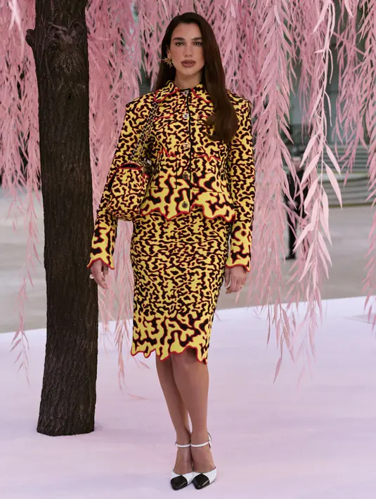 Dua Lipa tampil menyala dengan setelan blazer, rok midi, hingga tas bermotif api. Aksen api dihidupkan dalam potongan pada outline busana [Chanel]