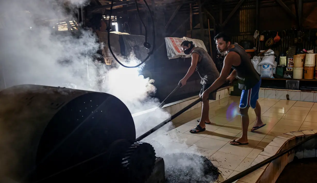 Para pekerja menyebarkan biji kopi robusta setelah disangrai secara tradisional di sebuah pabrik biji kopi kecil di Banda Aceh (14/11/2020). (AFP/Chaideer Mahyuddin)