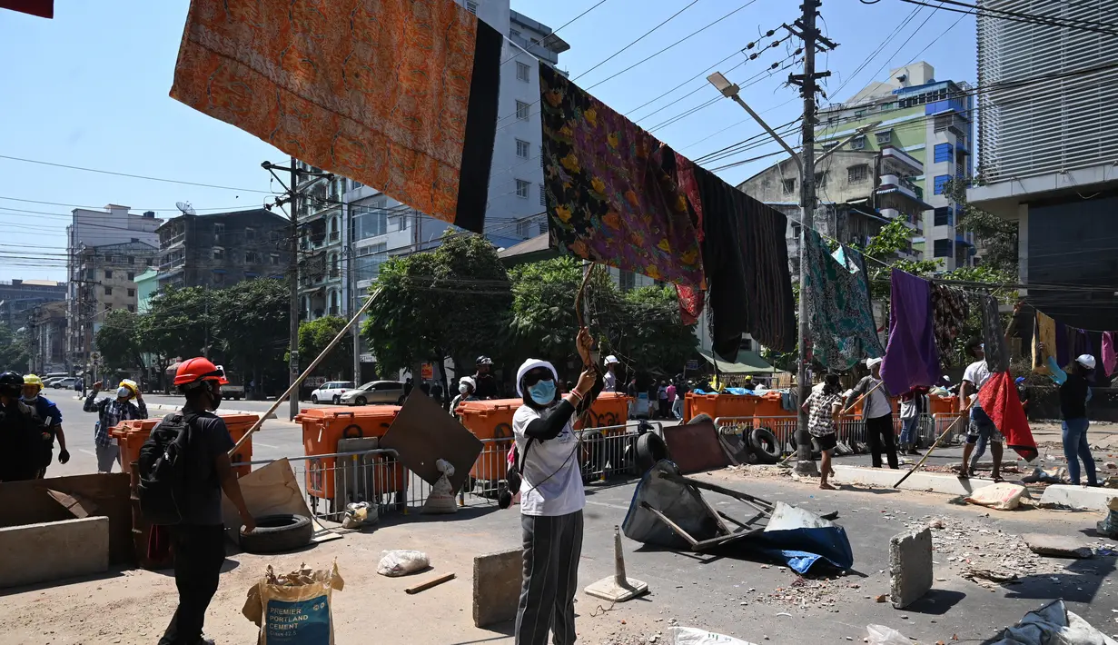 Pengunjuk rasa menggantung pakaian tradisional Myanmar bernama longyi di seberang jalan selama demonstrasi menentang kudeta militer di Yangon, Senin (8/3/2021). Para pengunjuk rasa membentangkan jemuran kain yang biasa dipakai perempuan untuk memperlambat gerak polisi dan tentara. (STR/AFP)