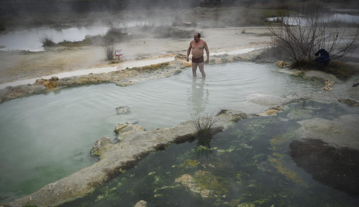 Seorang pria menikmati air panas di mata air mineral alami pada hari musim dingin di dekat desa Rupite, Bulgaria (2/2/2022). Penduduk setempat percaya bahwa air mineral menyembuhkan banyak penyakit dan gangguan. (AFP/Nikolay Doychinov)