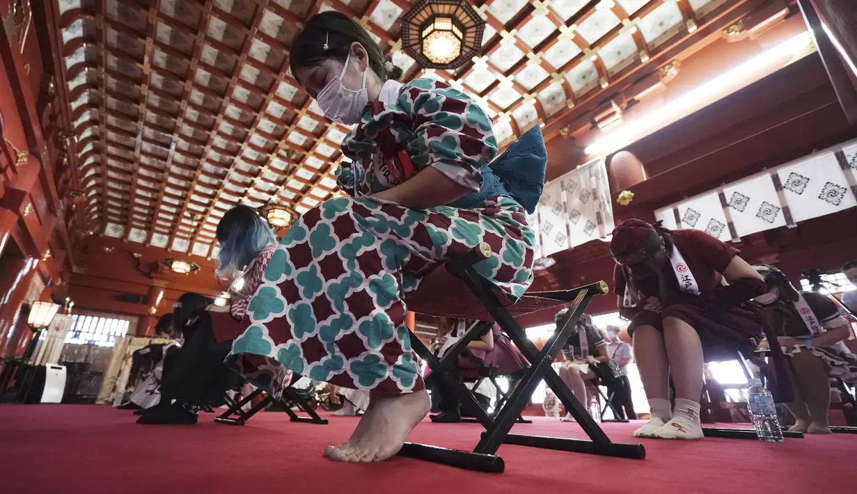 Para karyawan yang mengenakan kostum pelayan dari beberapa kafe bertema pembantu di Akihabara berdoa selama pertemuan doa untuk perlindungan dari COVID-19 dan untuk bisnis yang berkembang pesat di kuil Kanda Myojin, Tokyo (25/7/2020). (AP Photo/Eugene Hoshiko)