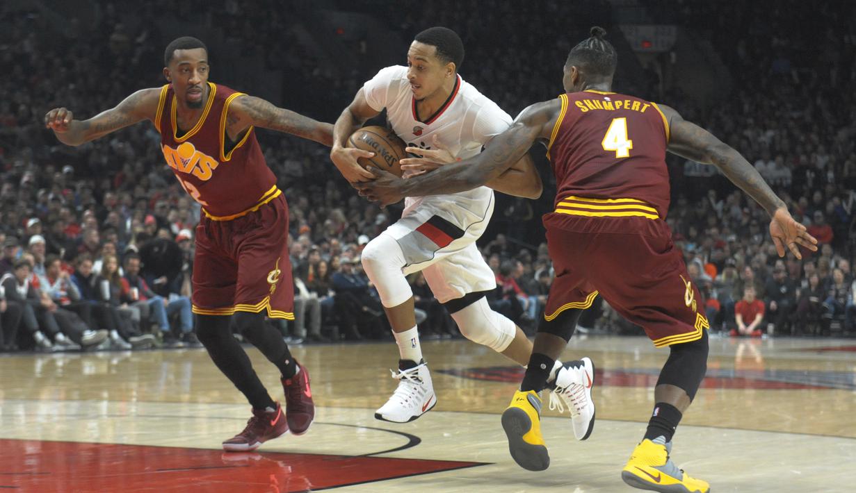 Pemain Portland Trail Blazers, C.J. McCollum menggiring bola melewati hadangan dua pemain Cleveland Cavaliers pada laga NBA basketball game di oda Center, Portland (11/1/2016). Blazers menang 102-86.  (AP/Steve Dykes)