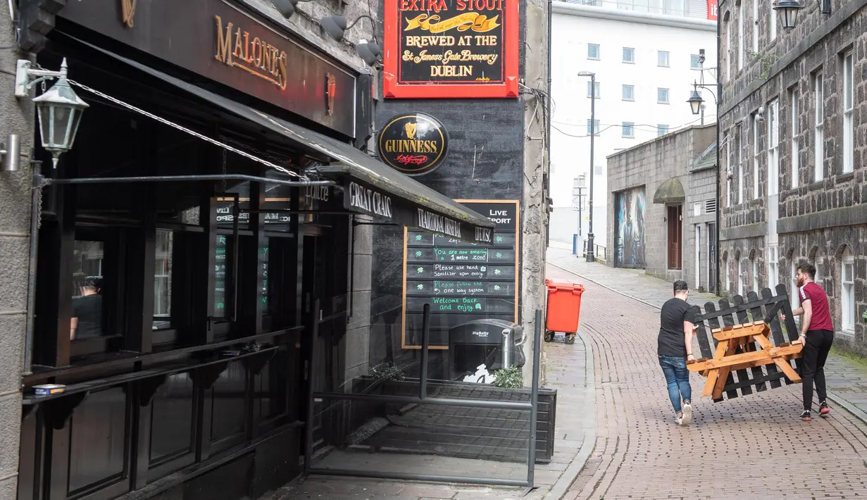Staf memindahkan meja luar ruangan dari sebuah pub menyusul pemberlakuan lockdown setelah jumlah kasus virus corona melonjak di Skotlandia, Kamis (6/8/2020). Pemerintah Kota Aberdeen mencatat puluhan kasus virus korona baru dalam minggu ini. (Michal Wachucik / POOL / AFP)