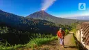 Warga berjalan melewati jalan yang memiliki kemiringan cukup tinggi dengan latar belakang Gunung Merapi di Dusun Tempel, Boyolali, Jawa Tengah, Senin (6/5/2024). (merdeka.com/Arie Basuki)