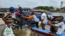 Sejumah pria memuat sepeda motor ke atas kapal saat pulang kampung ke pulau terpencil jelang Idul Fitri di Banda Aceh, Kamis (21/5/2020). Hari Raya Idul Fitri menandai berakhirnya bulan suci Ramadan. (CHAIDEER MAHYUDDIN/AFP)