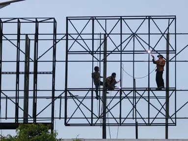 Pekerja menyelesaikan pembuatan papan reklame di jalan Gadjah Mada, Jakarta, Selasa (13/12). Pemerintah DKI Jakarta akan menyusun rencana penataan terhadap reklame yang tidak beraturan di jalur protokol. (Liputan6.com/Gempur M. Surya)