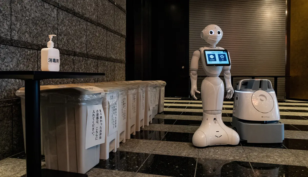 Robot Pepper (tengah) dan Whiz (kanan) berdiri di lobi hotel yang diubah menjadi lokasi karantina pasien COVID-19, Tokyo, Jepang, Jumat (1/5/2020). Robot Pepper dan Whiz dikerahkan ke area merah yang memiliki risiko tinggi terinfeksi virus corona COVID-19. (Philip FONG/AFP)