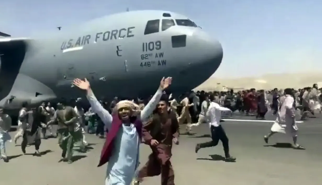 Ratusan orang berusaha menaiki pesawat angkut C-17 Angkatan Udara AS di landasan bandara internasional, di Kabul, Afghanistan (16/8/2021).  Di tengah kekacauan pasca direbutnya Ibukota Kabul oleh pasukan Taliban, dua warga jatuh dari pesawat militer Amerika Serikat. (Verified UGC via AP)