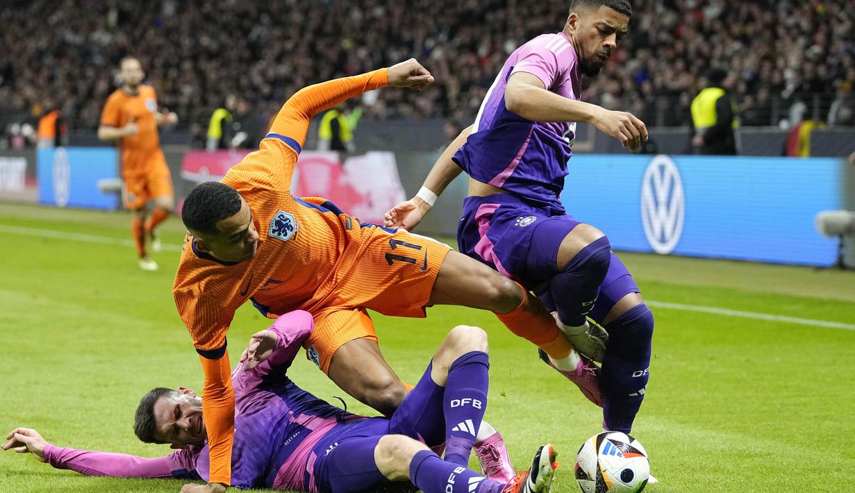 Pemain Jerman, Pascal Gross dan Benjamin Henrichs menghadang pemain Belanda, Cody gakpo, pada laga persahabatan di Stadion Deutsche Bank Park, Frankfurt, Rabu (27/3/2024). (AP Photo/Martin Meissner)