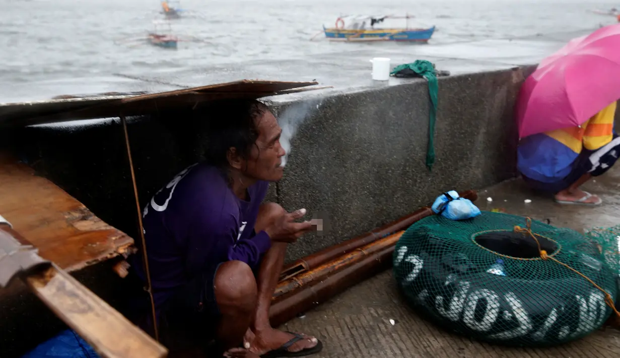 Seorang nelayan saat berlindung di trotoar ditengah cuaca buruk akibat Topan Nepartak yang menerpa di Manila Bay, Filipina, Jumat (8/7). (REUTERS/Erik De Castro)
