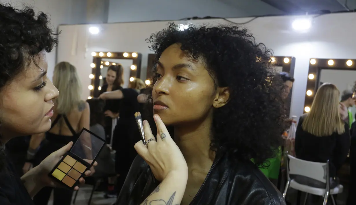 Model saat dirias wajahnya di belakang panggung sebelum tampil membawakan busana koleksi Beira selama Sao Paulo Fashion Week di Sao Paulo, Brasil (16/10/2019). SPFW ke-48 akan berlangsung hingga 18 Oktober.  (AP Photo / Nelson Antoine)