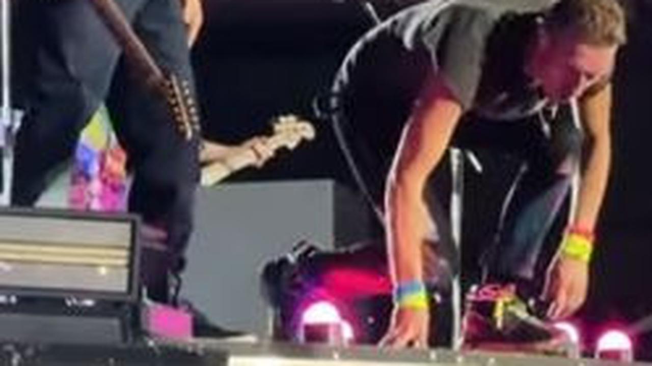 Usai menghentikan penampilan mereka, Chris Martin dan gitaris Coldplay, Johnny Buckland, melihat ke bawah dari tepi panggung untuk memastikan penonton tersebut baik-baik saja.