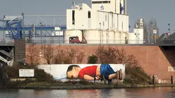 Pembuat grafiti, Justus Becker dan Oguz Sen melukis mural bergambar Aylan Kurdi, bocah Suriah yang jasadnya ditemukan di pantai barat daya Turki pada September 2015, di sebuah tembok di sungai Main, Frankfurt, Jerman, 10 Maret 2016. (Daniel ROLAND/AFP)