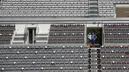 Orang-orang menonton pertandingan antara petenis Italia Jannik Sinner dan petenis Prancis Ugo Humbert pada turnamen tenis Italia Terbuka di Foro Italico, Roma, Selasa (10/5/2021). Pertandingan tersebut dimainkan tanpa penonto karena pembatasan COVID-19. (AP Photo/Alessandra Tarantino)