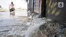 Pengendara motor melintasi rembesan air dari tembok saat banjir rob merendam Kompleks Perumahan Pantai Mutiara, Pluit, Jakarta, Minggu (7/6/2020). (merdeka.com/Iqbal S. Nugroho)
