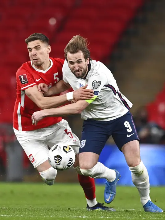 Pemain Inggris Harry Kane (kanan) memperebutkan bola dengan pemain Polandia Jan Bednarek pada pertandingan Grup I kualifikasi Piala Dunia 2022 di Stadion Wembley, London, Inggris, Rabu (31/3/2021). Inggris menang dengan skor 2-1. (Andy Rain/Pool via AP)