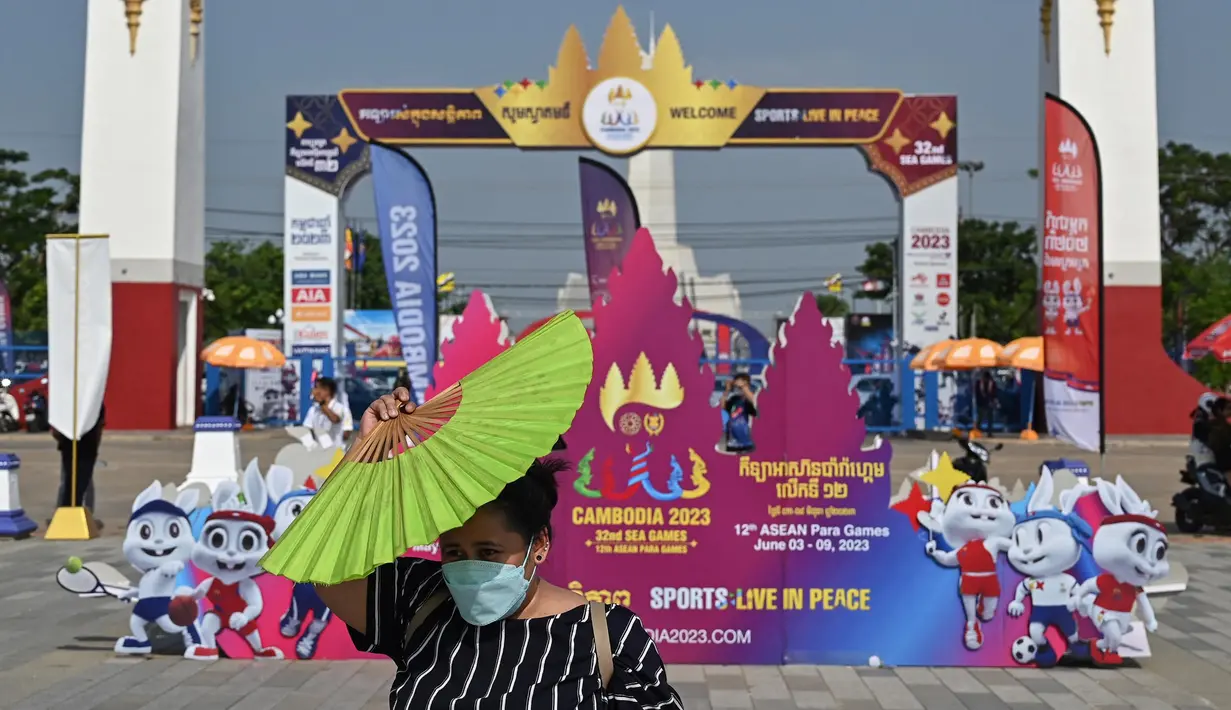 Seorang wanita memegang kipas angin untuk melindungi dirinya dari sinar matahari di luar Stadion Nasional Morodok Techo, Phnom Penh, Jumat 5 Mei 2023. (NHAC NGUYEN/AFP)