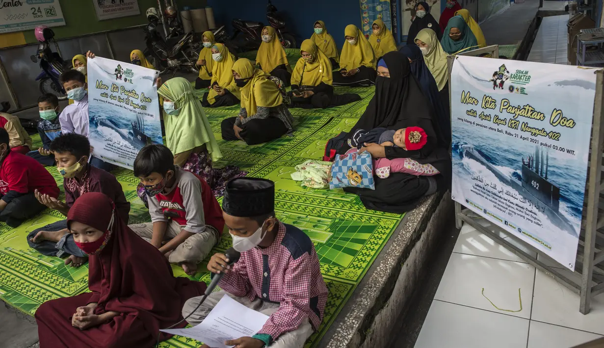 Siswa dan guru berdoa untuk 53 awak kapal selam KRI Nanggala 402 yang hilang di perairan Bali, di sebuah sekolah Islam di Surabaya, Jumat (24/4/2021). Kapal selam KRI Nanggala-402 yang membawa 53 awak dilaporkan hilang kontak di perairan Bali, Rabu, 21 April kemarin. (Juni Kriswanto/AFP)