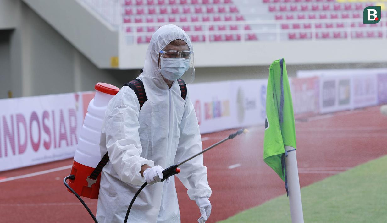 Petugas menyemprot bendera sepak pojok dengan disinfektan sebelum pertandingan antara Persikabo 1973 melawan Arema FC pada laga Piala Menpora di Stadion Manahan, Solo, Minggu (21/3/2021). (Bola.com/M Iqbal Ichsan)