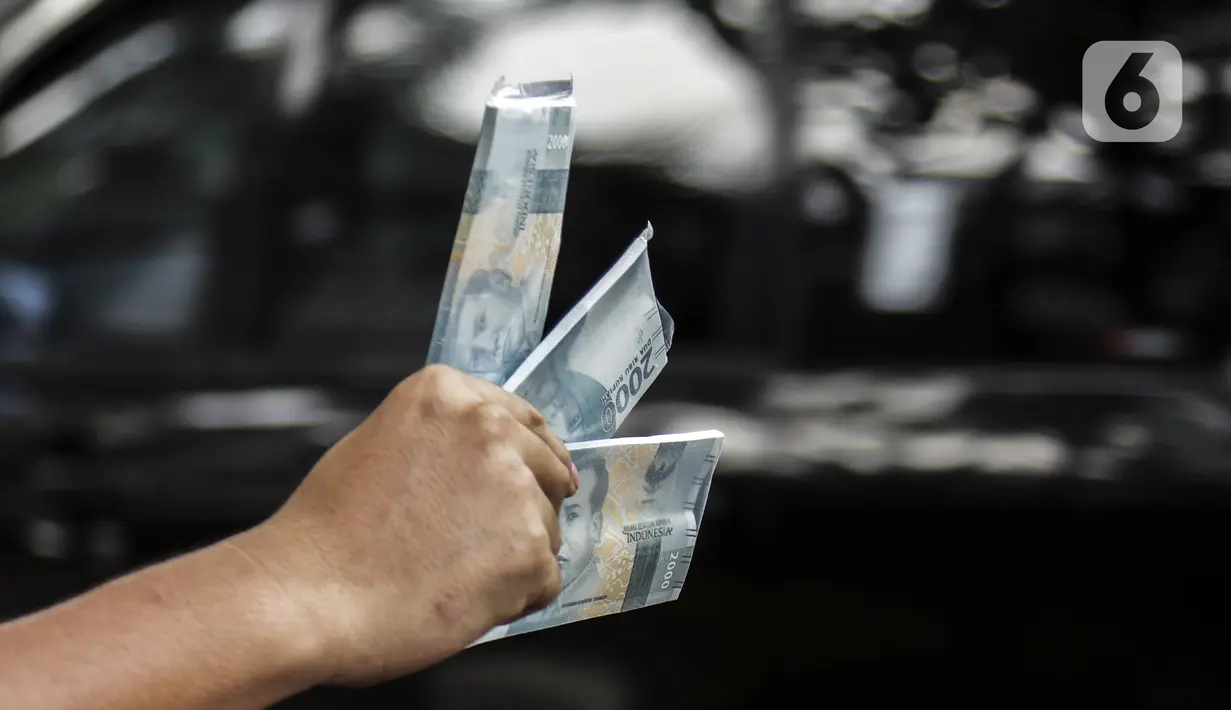 Penjual jasa penukaran uang menawarkan uang baru pecahan Rp 2.000 di kawasan Pondok Indah, Jakarta, Kamis (6/5/2021). Penjual jasa musiman tersebut mulai ramai menjelang Lebaran. (Liputan6.com/Johan Tallo)