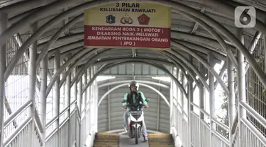 Pengendara sepeda motor melintasi rambu larangan saat melewati jembatan penyeberangan orang (JPO) Stasiun Pasar Minggu Baru, Jakarta, Selasa (10/3/2020). JPO tersebut kerap digunakan pengendara sepeda motor untuk menyeberang meski rambu larangan sudah dipasang. (merdeka.com/Iqbal Nugroho)
