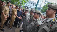 Gubernur dan Wakil Gubernur baru DKI, Anies Baswedan dan Sandiaga Uno menyapa Satpol PP yang sedang apel setibanya di Balai Kota Jakarta, Selasa (17/10). Anies dan Sandiaga keliling Balai Kota pada hari pertama mereka bertugas (Liputan6.com/Faizal Fanani)