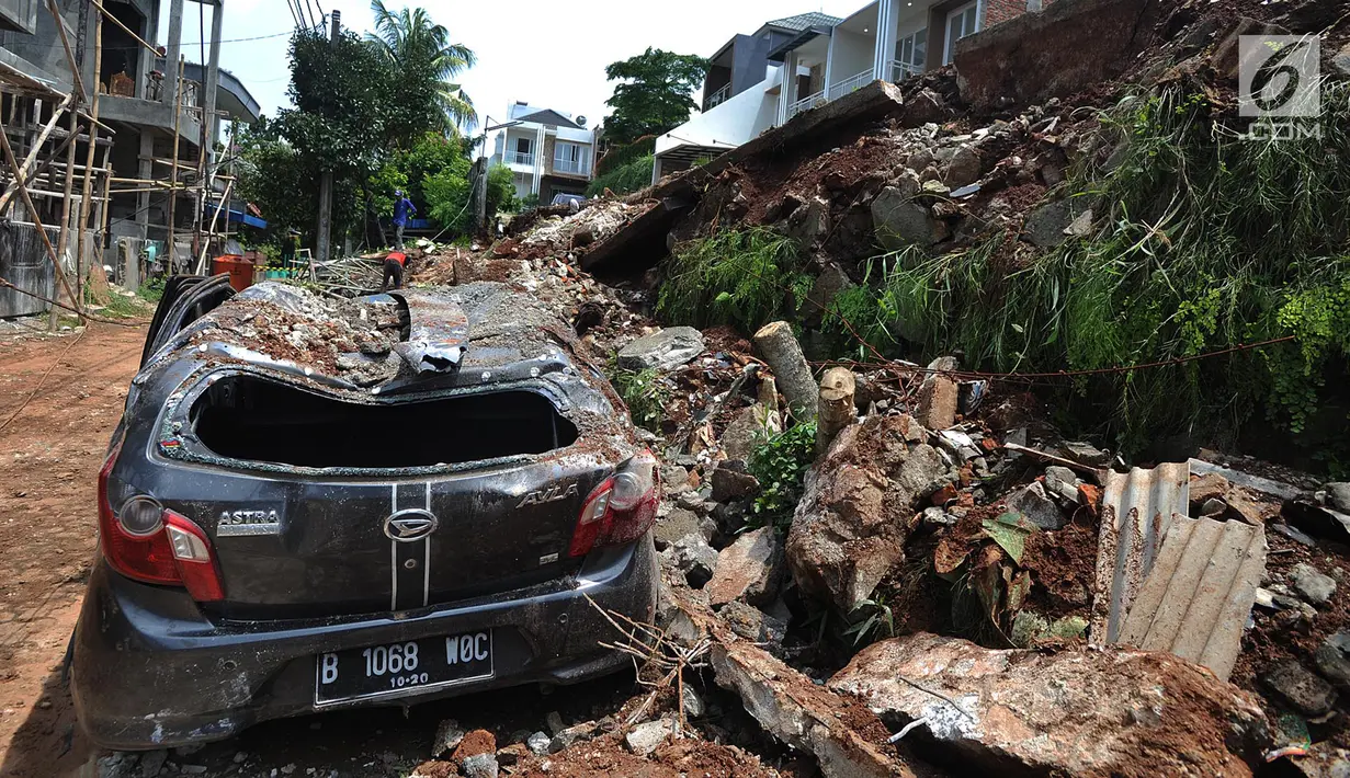 Sebuah mobil rusak setelah tertimpa material longsor tembok perumahan Lereng Indah di Perumahan Lereng Bukit Indah, Pondok Cabe Udik, Pamulang,Tangerang Selatan, Senin (8/4). Tembok perumahan sepanjang 25 meter dan tinggi enam meter itu longsor kemarin sore, Minggu (7/4). (merdeka.com/Arie Basuki)